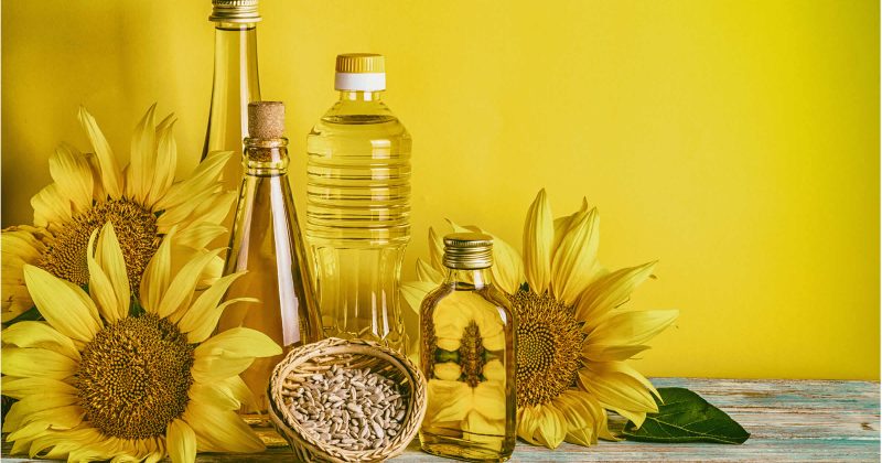 Multiple bottles of Sule sunflower oil alongside sunflowers and sunflower seeds