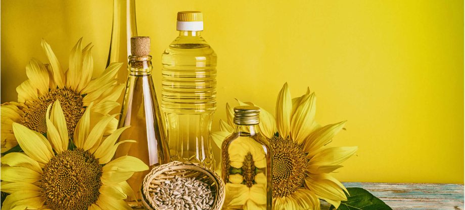 Multiple bottles of Sule sunflower oil alongside sunflowers and sunflower seeds